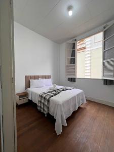 a white bedroom with a bed and two windows at Apto RUA DO LAZER in Santa Teresa