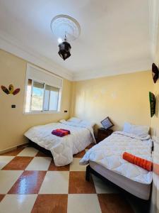 a bedroom with two beds and a checkered floor at Vitamin taliouine appartement in Taghazout