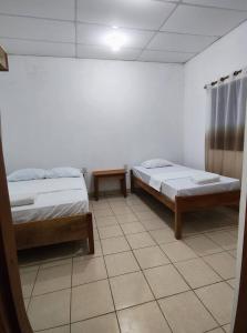 two beds in a room with a tiled floor at Hostal Jireh in Altagracia +2 photos