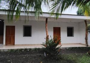 a white building with a palm tree in front of it at Hostal Jireh in Altagracia