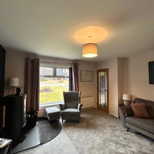 a living room with a couch and a chair and a tv at 6 Carn Dearg House in Aviemore