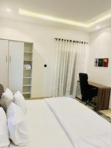 a bedroom with a bed and a desk and a chair at Dinems Apartment in Ikeja