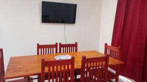 a wooden table with chairs and a television on a wall at Altos de la Villa House in Concepción del Uruguay