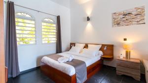 a bedroom with a large bed and two windows at Villa La Ressource in Le François +40 photos