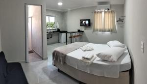 a bedroom with a white bed and a bathroom at Kitnet Moderna com Ar, Garagem e Wi-Fi Rápido in Votorantim