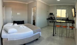 a bedroom with a large bed and a kitchen at Kitnet Moderna com Ar, Garagem e Wi-Fi Rápido in Votorantim