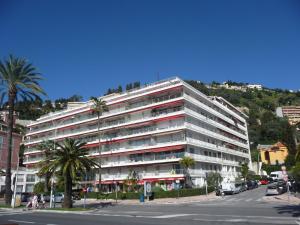 a large white building with palm trees in front of a street at Sea View Apartment - Residence Les Sablettes in Menton