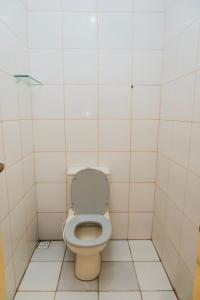 a bathroom with a toilet in a white tiled room at Casa Celeste in Boa Vista