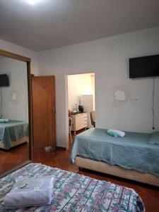 a bedroom with two beds and a television on the wall at Confort Suite 01 in Contagem