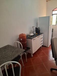 a kitchen with a counter and a refrigerator and a table at Confort Suite 01 in Contagem