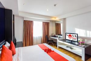 a hotel room with a bed and a desk with a computer at Nova Platinum Hotel in Pattaya South