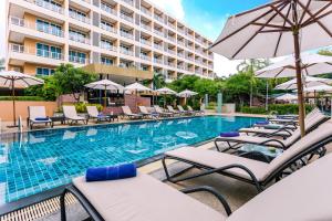 a pool with chairs and umbrellas next to a hotel at Nova Platinum Hotel in Pattaya South