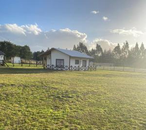 a white house in the middle of a field at Cabaña Paihuen in Puerto Octay