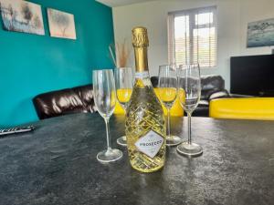 a bottle of wine sitting on a table with four wine glasses at Very Spacious 4 Bedroom house with large garden in Leamington Spa +13 photos