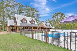 a house with a swimming pool and a fence at Standen Manor, Hunter Valley Country Estate & Stables in Belford
