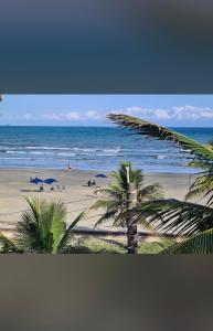 a view of a beach with palm trees and the ocean at Residêncial Allah in Peruíbe