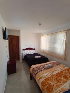 a bedroom with two beds and a television in it at Hotel CasaBlanca"Tablon de miraflores" in Cuenca