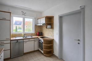 a kitchen with white cabinets and a sink and a window at cozy studio Brussels airport in Steenokkerzeel