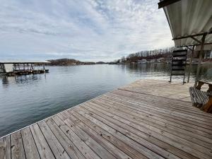 a wooden dock with a chair on the water at Fox's Den Your Lakefront Escape with Dock and Stunning Views in Rocky Mount