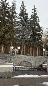 a stone wall with trees in front of a building at LIZA Home in Jermuk