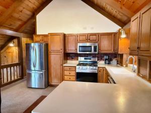 a kitchen with wooden cabinets and a stainless steel refrigerator at Fox's Den Your Lakefront Escape with Dock and Stunning Views in Rocky Mount +16 photos