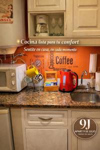 a kitchen with a counter top with a coffee sign on the wall at Apart 9 de julio in Salta