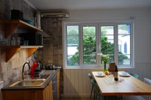 a kitchen with a wooden table and two windows at Vulcânica - Boutique Suites in Furnas São Miguel in Furnas