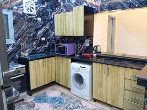 a kitchen with a washing machine and a microwave at Nour House in Luxor