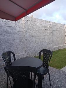 a black table and two chairs in front of a brick wall at Hostel de clecia in Extremóz