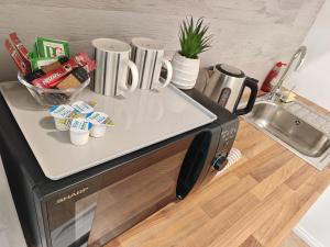 a kitchen counter with a microwave with cups on it at Lilac Studio - Self Contained One-Bed Studio Flat in Oxford