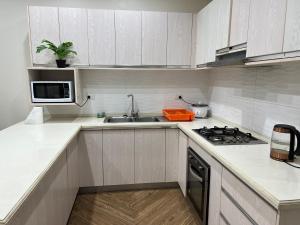 a white kitchen with a sink and a microwave at Waiyavi Apartments in Lautoka