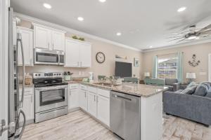a kitchen with white cabinets and a living room at SEA-Bound STR in Pensacola