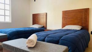 two beds with blue sheets in a room at Casa Bugambilia Progreso #1 in Progreso