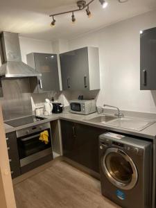 a kitchen with a washing machine and a sink at Wilsuel Haven-2Bedroom Aprt in Wolverhampton