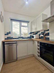 a kitchen with white cabinets and a window at Cornish coastal escape in Bude in Bude