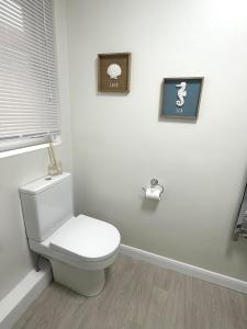 a bathroom with a toilet with two pictures on the wall at Cornish coastal escape in Bude in Bude +24 photos