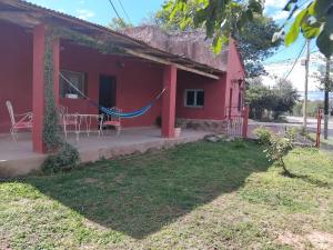 a red house with a hammock outside of it at Casona Estación Cabra Corral in Coronel Moldes