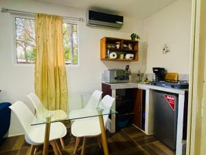 a small kitchen with a glass table and white chairs at Quinta el Refugio in Masaya