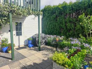 a garden with a table and flowers and a house at Cosy Orchard Loft - Fast WIFI in Tauranga