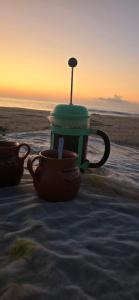 a tea pot and cups sitting on the beach at Chacahua Cabañas LAUD in Guayabas