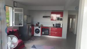 a kitchen with red cabinets and a washing machine at Appartement Ti Coquelicot in Rivière-Salée