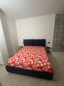 a bedroom with a bed with a red bedspread with flowers at Nuvole e Miracoli - foresteria in Bagnolo Mella