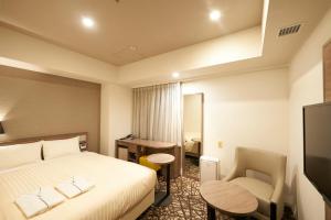 a hotel room with a bed, desk and a television at Sotetsu Fresa Inn Ginza-Nanachome in Tokyo