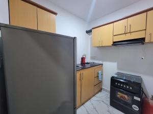 a kitchen with a black refrigerator and wooden cabinets at DALENT RESiDENCE in Brusubi