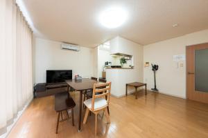a living room with a table and chairs and a television at アルカディアｋ in Aomori