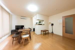a living room with a table and chairs and a television at アルカディアｋ in Aomori