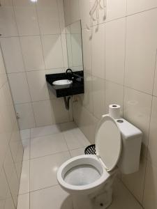 a white bathroom with a toilet and a sink at Hotel Lalique in São Paulo