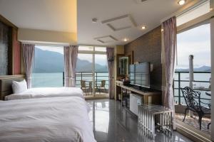 1 dormitorio con cama, TV y balcón en Shui Sha Lian Hotel - Harbor Resort, en Yuchi