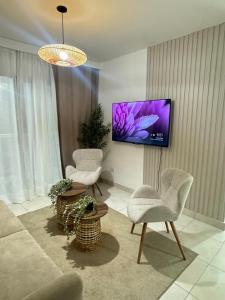 a living room with two chairs and a tv on the wall at Estilo y comodidad a pasos de la playa in La Romana
