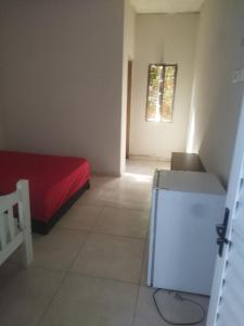 a small bedroom with a red bed and a window at chácara Cantagalo in Caraguatatuba
